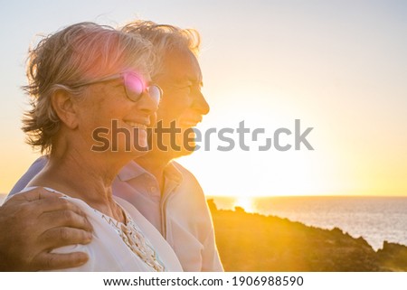 Couple of two happy seniors having fun in holiday trip together at vacations in the beach with the sea or ocean at the background