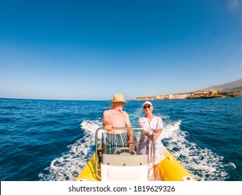 Couple Of Two Happy Seniors And Mature People Using And Driving A Small Boat Or Dinghy In The Middle Of The Sea Or Ocean - Old Man And Woman Enjoying Summer