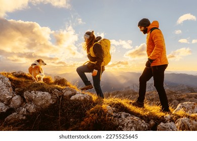 couple of two mountaineers with their adopted dog on a mountain route at sunset. Traveling and playing sports with pets. outdoor activities and adventure. - Powered by Shutterstock