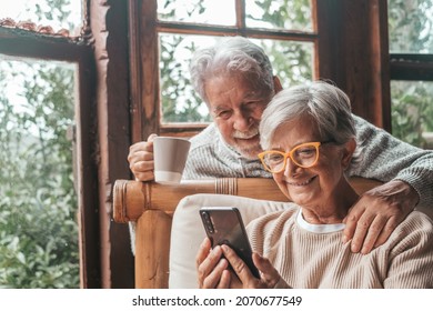 Couple of two old and mature people at home using phone together in sofa. Senior use smartphone having fun and enjoying looking at it. Leisure and free time concept in the living room - Powered by Shutterstock