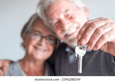 couple of two seniors after buy a new house or car and go to live together - man holding a key and mature man and woman looking at it - Powered by Shutterstock