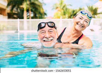 couple of two seniors hugged in the water of swimming pool - active man and woman doing exercise together at the pool - hugged with love