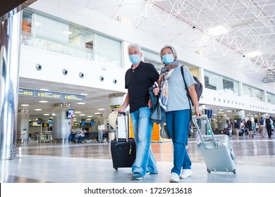 couple of two seniors or mature people walking in the airport going to their gate and take their flight wearing medical mask to prevent virus like coronavirus or covid-19 - carrying luggage or trolley - Powered by Shutterstock