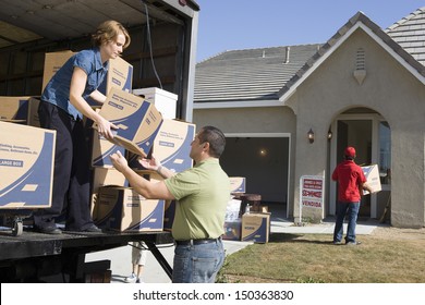 Couple Unloading Moving Boxes From Truck Into New House