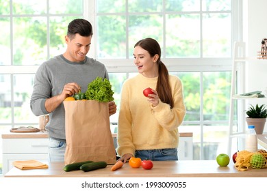 Couple unpacking fresh products from market in kitchen - Powered by Shutterstock