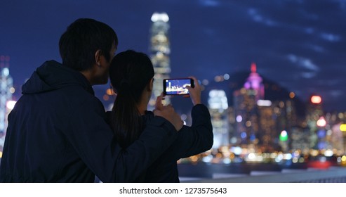 Couple Use Of Mobile Phone For Take Photo In Hong Kong At Night