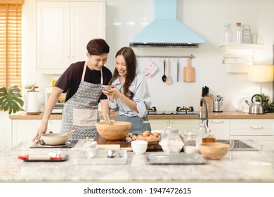 A Couple Uses Their Smart Phone To Take A Picture While Admiring His Wife's Cooking Work With A Happy Face In An Atmosphere Of Love