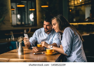 couple using cellphone while enjoying coffee in cafeteria