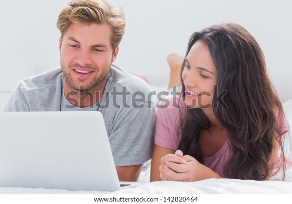 Couple using computer\
together in bed