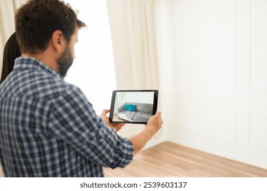 Couple is using a digital tablet and augmented reality technology to visualize furniture placement in their new house