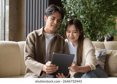 Couple using digital tablet computer in cafe while having coffee