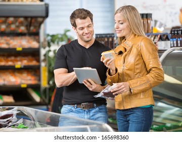 Couple using digital tablet while checking ingredients of product at butcher's shop - Powered by Shutterstock