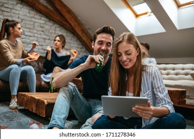Couple using digital tablet while their friends eating pizza behind them - Powered by Shutterstock