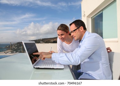 Couple Using Laptop Computer Outside The House