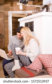 Couple Using Laptop In Log Cabin