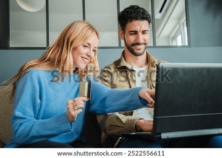 Couple using a laptop to make an online purchase with a credit card, smiling while shopping together, highlighting e-commerce, digital payments, and convenient online shopping from home. High quality
