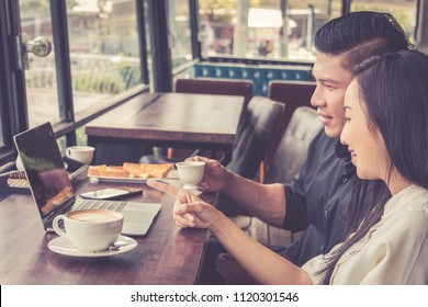 Couple using laptop while relaxing and drinking coffee at coffee shop.
