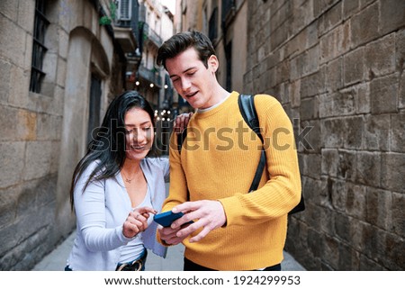 Couple using a mobile phone while walking outdoors.