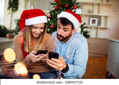 Couple Using Phone At Christmas Time