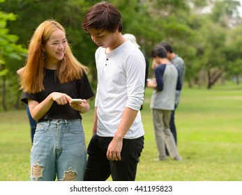 Couple Using Phone In Park