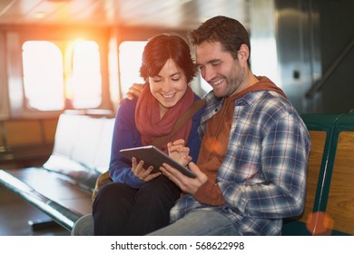 Couple using tablet computer on ferry