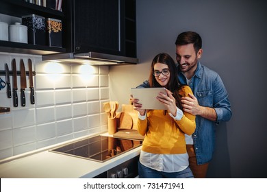 Couple Using Tablet In Kitchen.