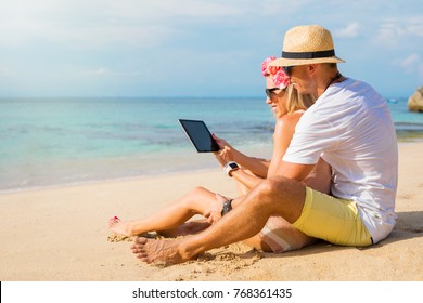 Couple using tablet on the beach - Powered by Shutterstock