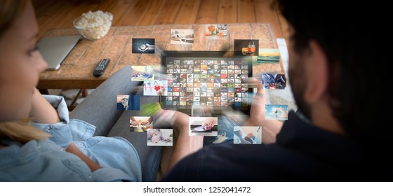 Couple using tablet for watching VOD service. Video On Demand television with abstract flying images
