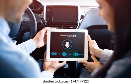 Couple Using Voice Assistant App On Tablet Computer Sitting In Smart Car. Modern Technology Services. Back View, Selective Focus