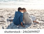 Couple, vacation or beach trip sitting on blanket for picnic or relaxing on seashore getaway. Love, man and woman together happy in nature by ocean for romantic date, sunset or holiday in California