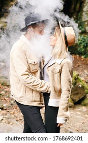 Couple in vape cloud. Two in smoke. Tourists in cold autumn forest with vape. Man and women in smoke. Two smokers. Beautiful couple in fog. E-cigarettes and people