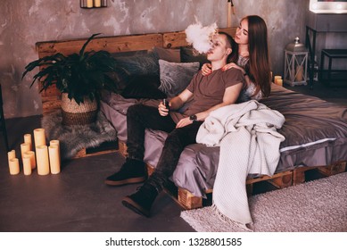 Couple vaping. Young man and woman blowing smoke while sitting on a wooden bed. The concept of relationships and vape dependence with copy space