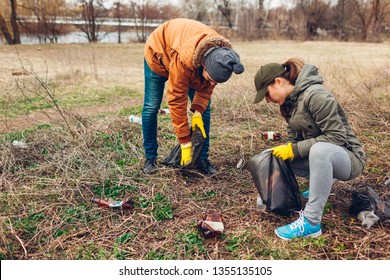 Couple Of Volunteers Cleaning Up The Trash In Park. Picking Up Garbage Outdoors. Ecology And Environment Concept