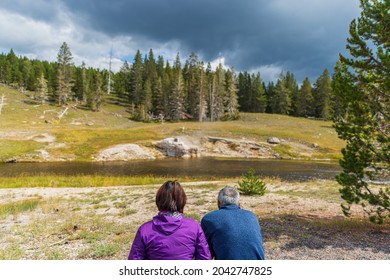 Couple Waiting For The Eruption Of Riverside Geyser In Old Faithful Basin, Yellowstone National Park