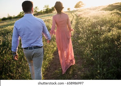 Couple Walking Away In The Field At Sunset