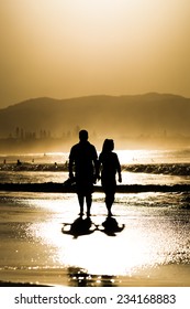 A Couple Walking At The Beach Of Byron Bay, Australia At Sunset