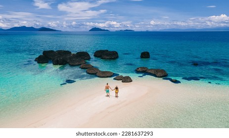 couple walking at the beach of Koh Kham Trat Thailand, aerial view of the tropical island near Koh Mak Thailand. white sandy beach with palm trees and big black boulder stones in the ocean - Shutterstock ID 2281637293