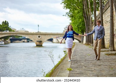 Couple Is Walking By The Seine Embankment In Paris