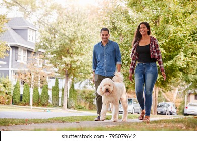 Couple Walking Dog Along Suburban Street - Shutterstock ID 795079642