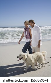 Couple Walking Dog On Beach