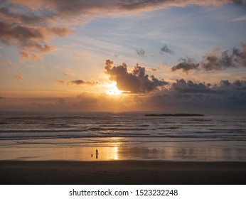 Couple Walking Dog On Oregon Beach At Sunset