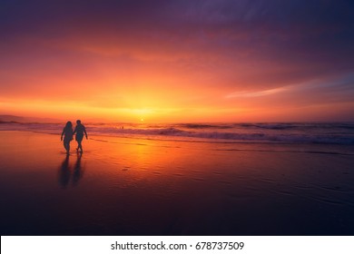 Couple Walking On Beach At The Sunset