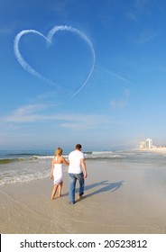 Couple Walking On Beach Under Heart Skywriting