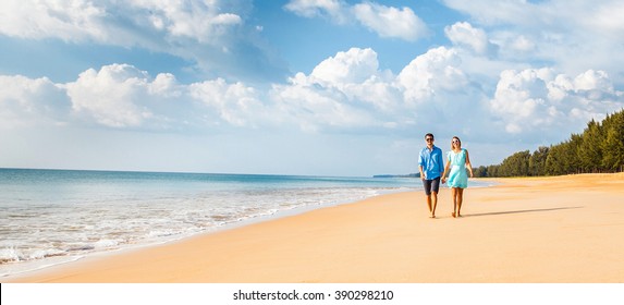 Couple walking on beach. Young happy interracial couple walking on beach smiling holding around each other.  Banner