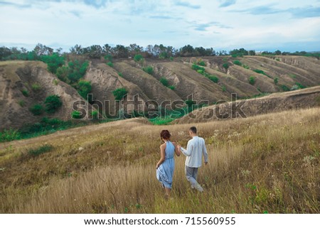 Couple walking on hill and field in the summer. Rear view