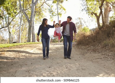 Couple Walking On Rural Path Lifting Daughter, Full Length