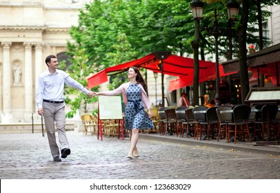 Couple Walking In Paris Near An Outdoor Cafe