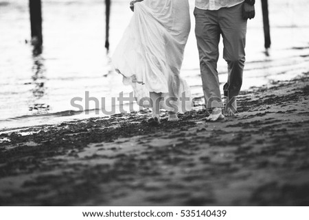 Couple walking seaside beach, love story concept near sea at sunset, holding each others hands,  black and white