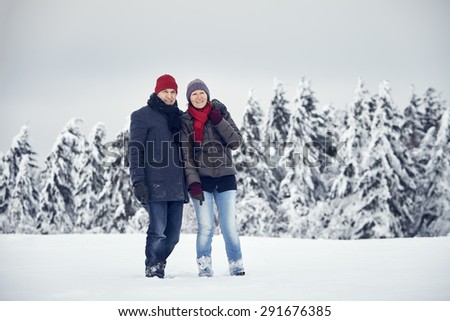 Couple walking in the snow laughing together and having fun