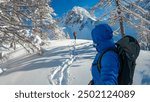 Couple walking in snow shoes with panoramic view of snow capped mountain peak Bielschitza in Karawanks, Bärental, Carinthia, Austria. Ski touring in winter wonderland in the Austrian Alps on sunny day